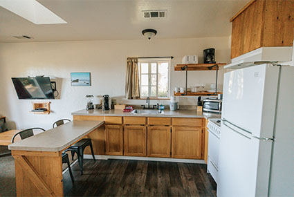 Photo of a full-sized kitchen, with a refrigerater, ample counter space, and a breakfast bar.